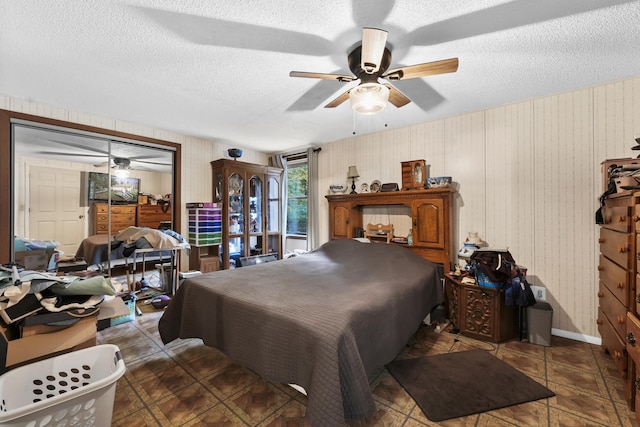 bedroom with dark tile patterned flooring, a closet, ceiling fan, and a textured ceiling