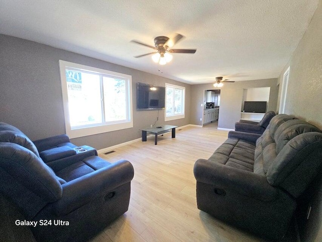 living room featuring a textured ceiling, light hardwood / wood-style floors, and ceiling fan