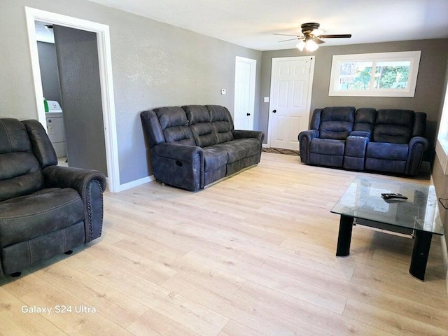 living room featuring ceiling fan, washer / clothes dryer, and light wood-type flooring