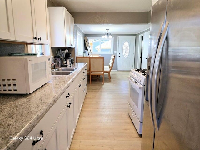 kitchen featuring sink, white appliances, light hardwood / wood-style flooring, white cabinetry, and an inviting chandelier