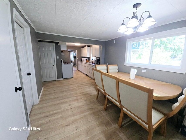 dining space with light hardwood / wood-style floors, ornamental molding, and an inviting chandelier