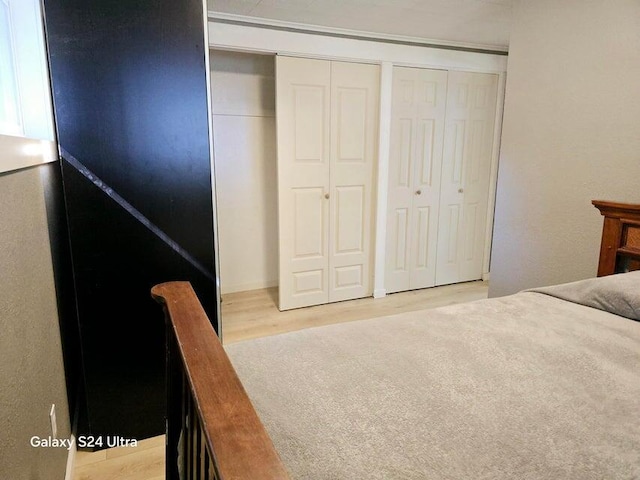 bedroom with multiple closets and light hardwood / wood-style flooring