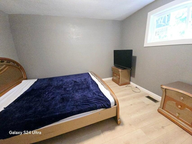 bedroom featuring lofted ceiling and light hardwood / wood-style flooring