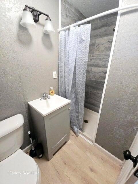 bathroom with walk in shower, vanity, and toilet