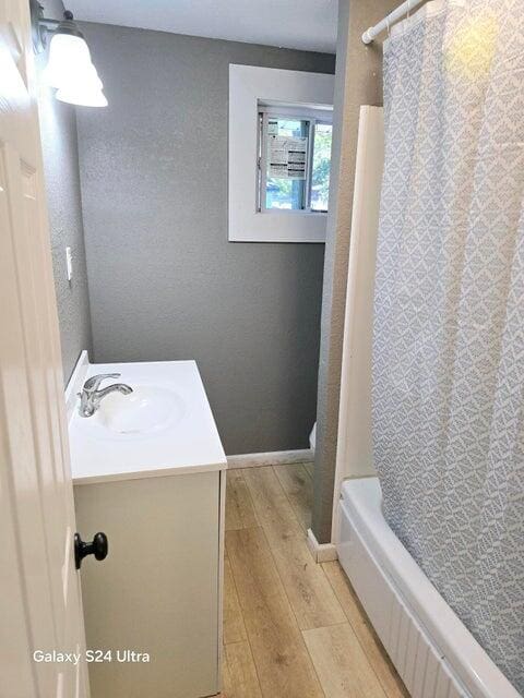 bathroom with vanity, hardwood / wood-style flooring, and shower / bath combo with shower curtain