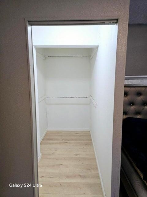 walk in closet with light hardwood / wood-style flooring