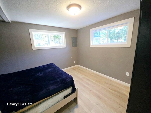 bedroom featuring wood-type flooring, a textured ceiling, and multiple windows