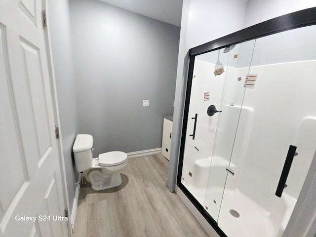 bathroom featuring walk in shower, wood-type flooring, vanity, and toilet