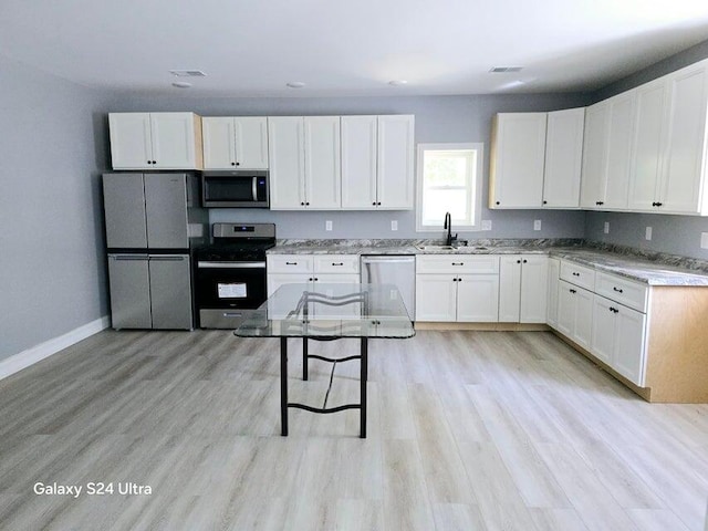 kitchen with light wood-type flooring, sink, stainless steel appliances, and white cabinets