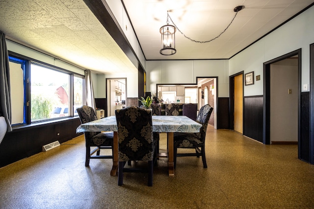 dining space featuring an inviting chandelier and wooden walls