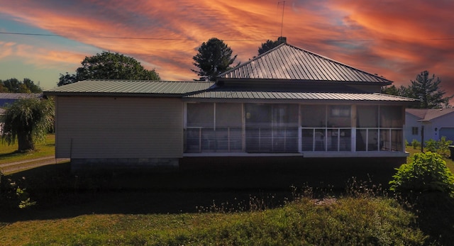 property exterior at dusk featuring a sunroom