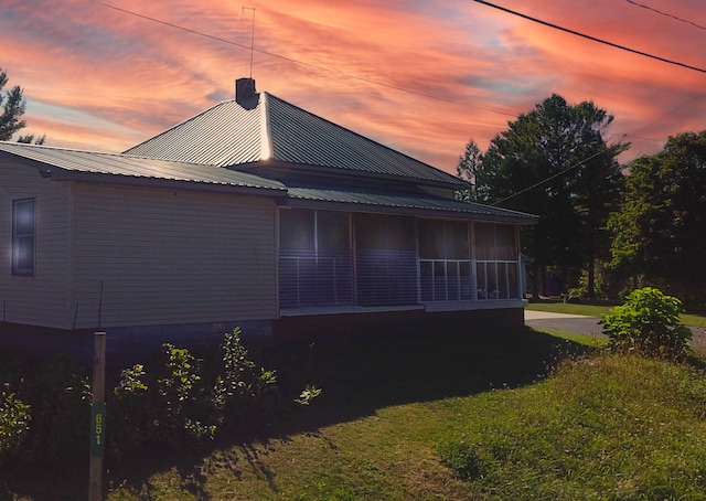 property exterior at dusk with a sunroom and a yard