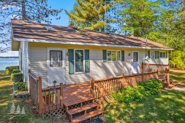 rear view of property featuring a yard and a wooden deck