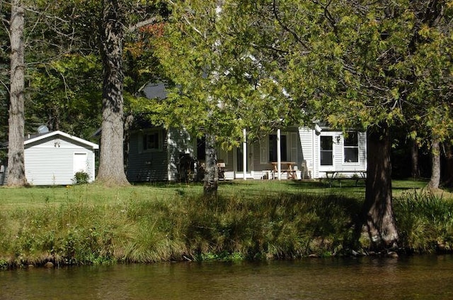 view of front of house with a storage shed and a water view