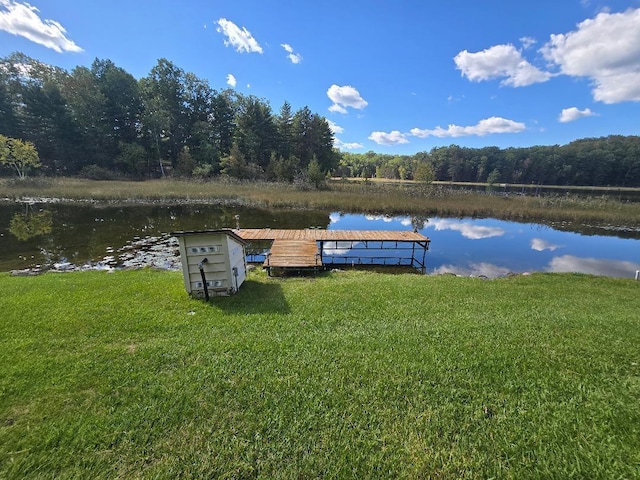 view of dock with a lawn and a water view