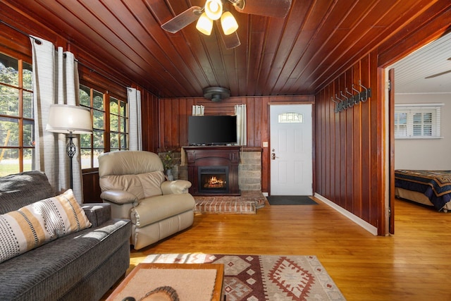 living room featuring ceiling fan, wooden walls, wooden ceiling, and light wood-type flooring