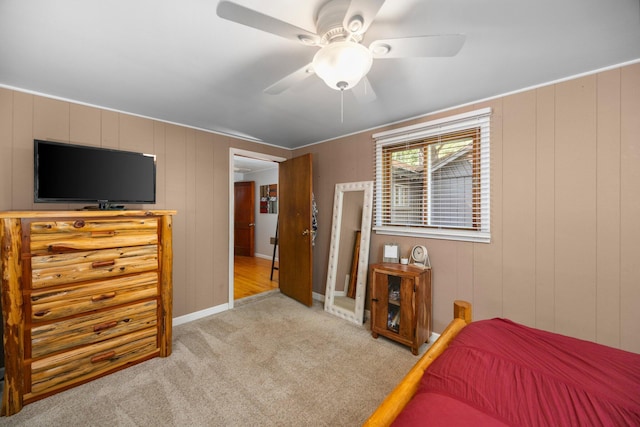 carpeted bedroom with ceiling fan and wood walls