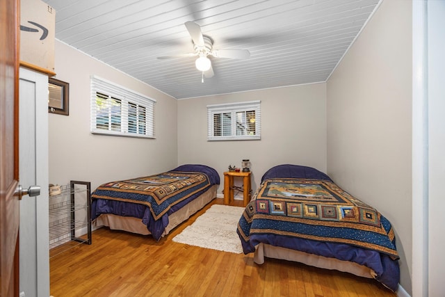 bedroom with multiple windows, ceiling fan, and wood-type flooring