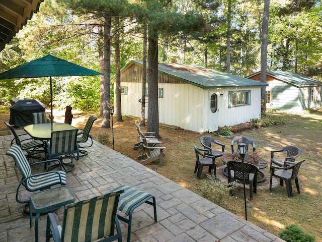 view of patio with area for grilling, an outbuilding, and an outdoor fire pit