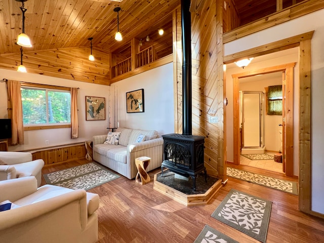 living room with a wood stove, wooden walls, high vaulted ceiling, hardwood / wood-style flooring, and wooden ceiling