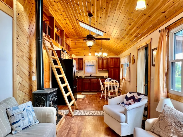 living room with a healthy amount of sunlight, vaulted ceiling, hardwood / wood-style floors, and a wood stove