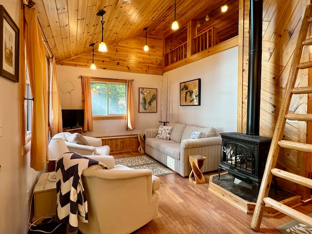 living area with light hardwood / wood-style flooring, a wood stove, high vaulted ceiling, and wood ceiling