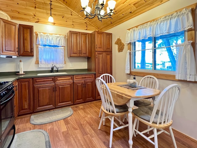 kitchen featuring a chandelier, light hardwood / wood-style floors, lofted ceiling, decorative light fixtures, and black stove