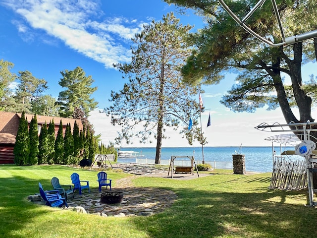 view of home's community with a lawn, a water view, and a fire pit