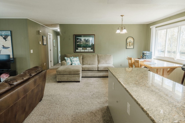 living room with crown molding, a chandelier, and light colored carpet