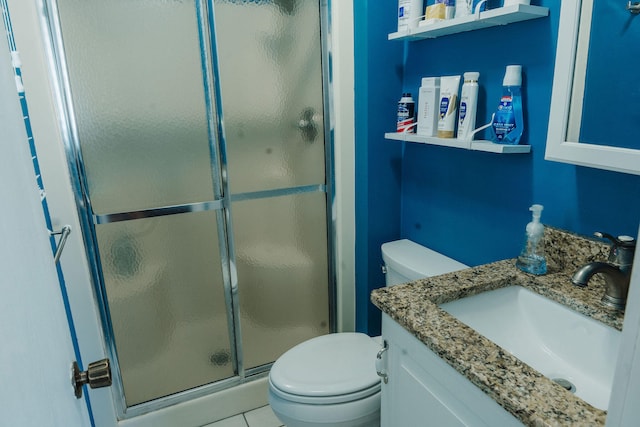 bathroom with vanity, toilet, tile patterned floors, and a shower with door