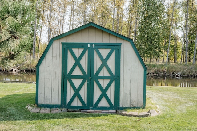 view of outdoor structure featuring a lawn and a water view