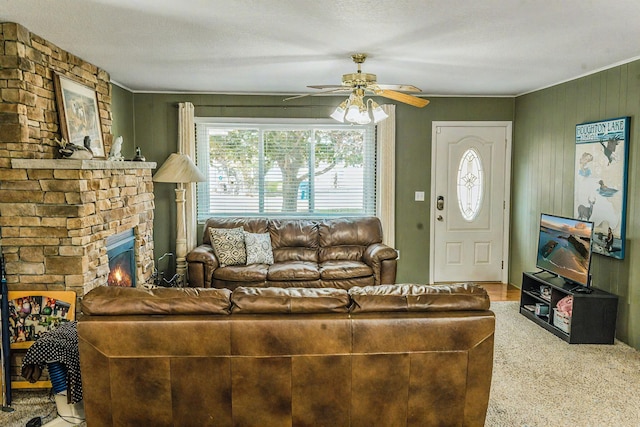 living room featuring a textured ceiling, a fireplace, carpet flooring, and ceiling fan