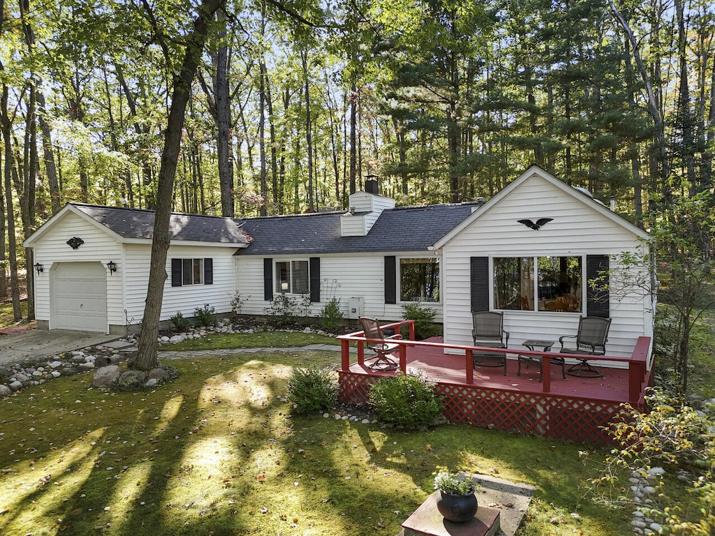 rear view of house with a yard, a deck, and a garage