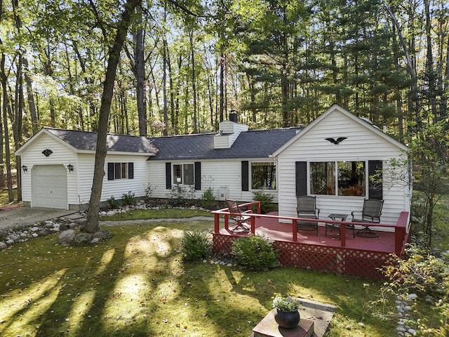 rear view of house with a yard, a deck, and a garage