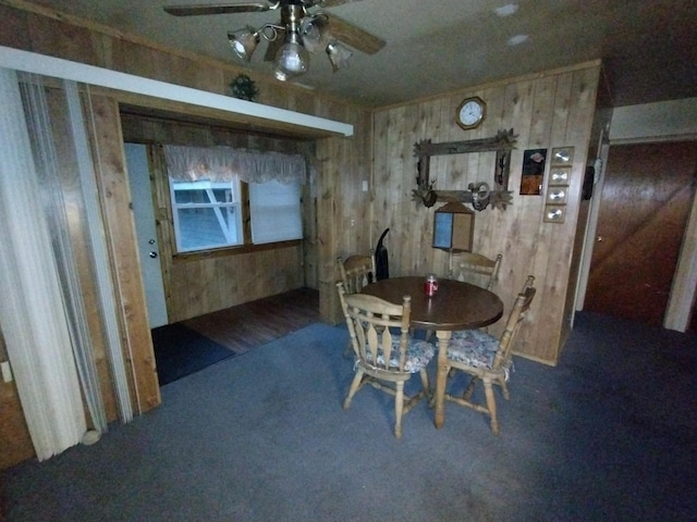 carpeted dining space with ceiling fan and wood walls