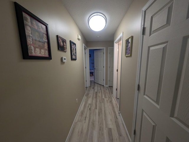 hallway featuring light hardwood / wood-style flooring and a textured ceiling