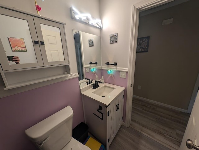 bathroom with toilet, vanity, and wood-type flooring