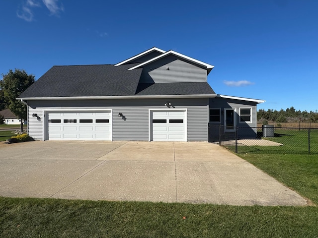 view of front of home featuring roof with shingles, a front yard, fence, a garage, and driveway