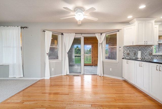 kitchen featuring light wood-type flooring, ceiling fan, tasteful backsplash, white cabinets, and a textured ceiling