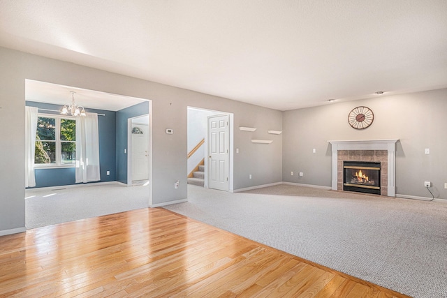 unfurnished living room featuring a notable chandelier, a tile fireplace, and hardwood / wood-style floors