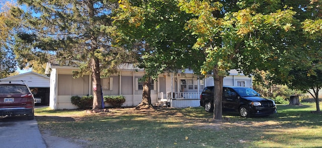 view of property hidden behind natural elements with a front yard and covered porch