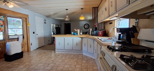 kitchen with white gas stove, sink, white cabinets, hanging light fixtures, and ceiling fan