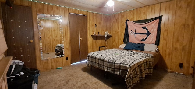 bedroom with ceiling fan, carpet floors, and wood walls