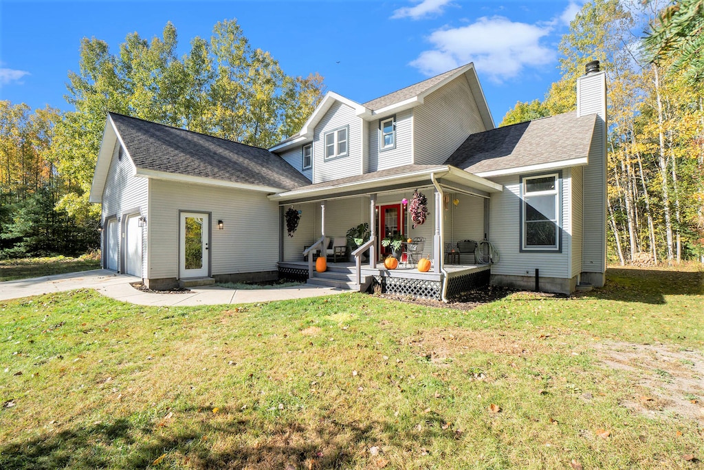 view of property featuring a garage, a porch, and a front lawn