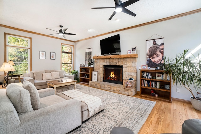 living room featuring ceiling fan, a fireplace, plenty of natural light, and light hardwood / wood-style floors