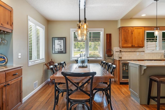 dining space featuring hardwood / wood-style flooring, a textured ceiling, and wine cooler