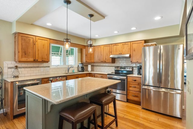 kitchen featuring light stone counters, stainless steel appliances, sink, a center island, and a breakfast bar area