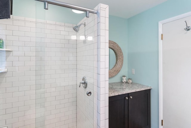 bathroom with tiled shower and vanity