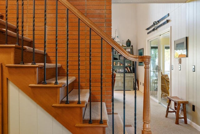 staircase featuring carpet floors and wooden walls