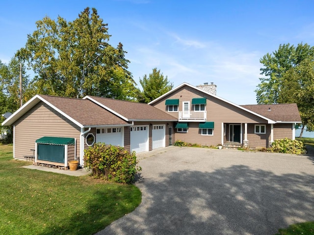 view of front of house featuring a balcony, a front yard, and a garage